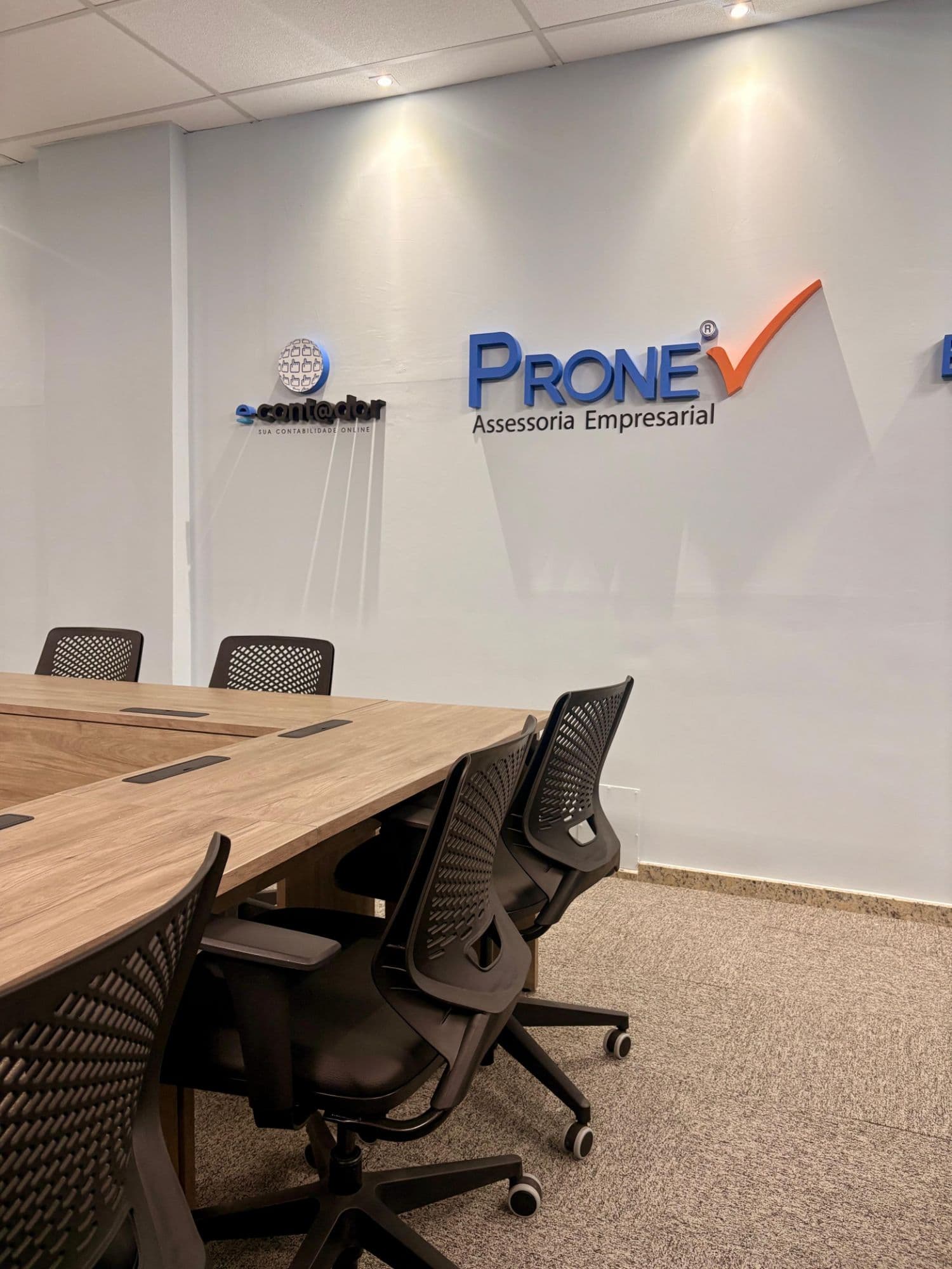 Sala de reuniões da PRONE, com os logotipos da PRONE Assessoria Empresarial e da e-cont@dor na parede