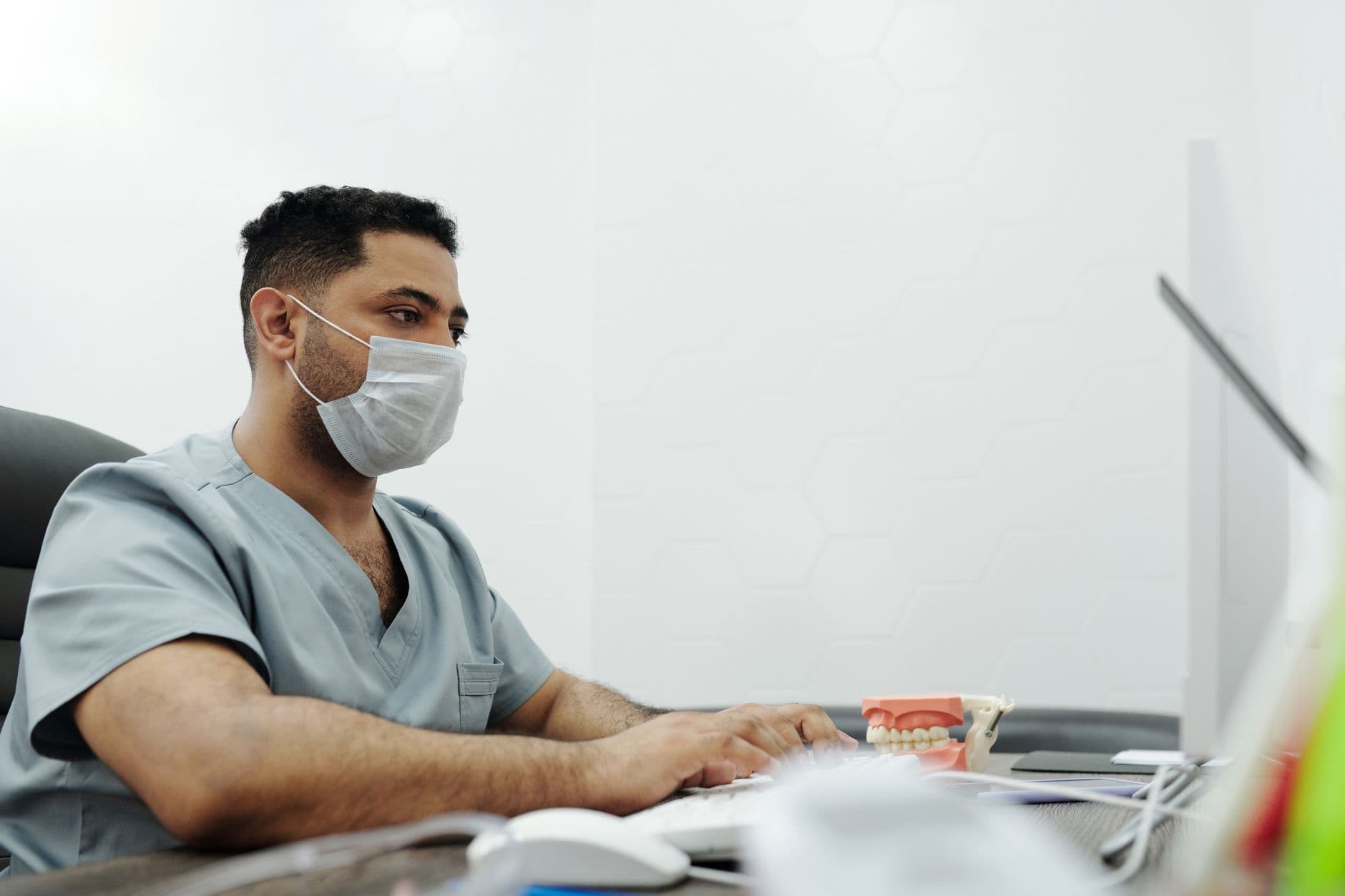 Médico em jaleco trabalhando no computador do consultório